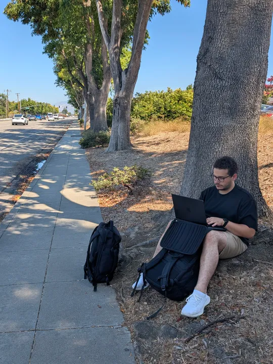 Kadir Lofca sitting on a sidewalk next to Apple Park in Cupertino.